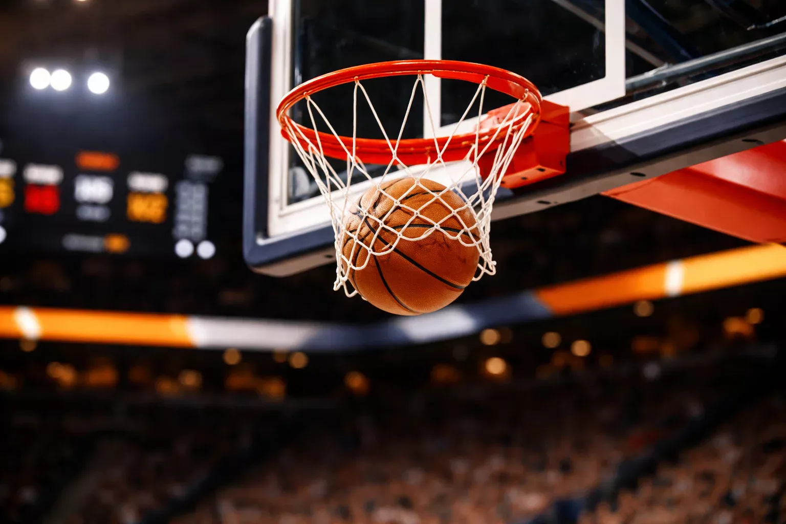 Basketballkorb mit Spielstand-Anzeige und orangefarbenem Ball im Flug